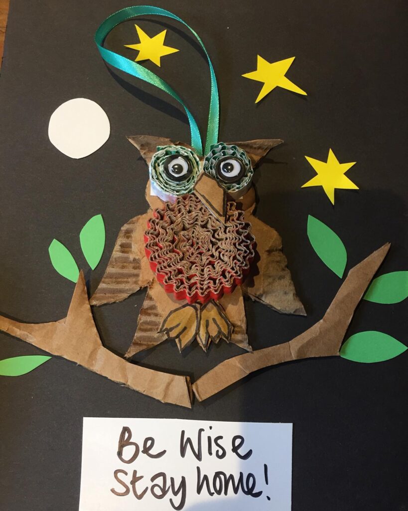 An owl made out of carboard with googly eyes. A note below reads Be Wise Stay Home! 